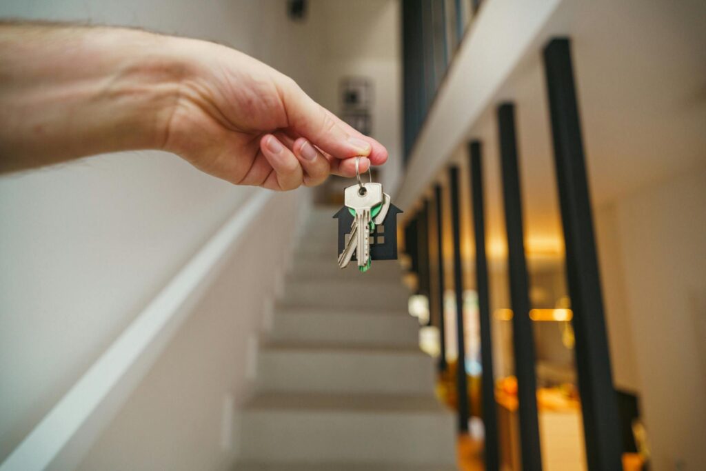 Someone holding keys with indoor house stairs in the background